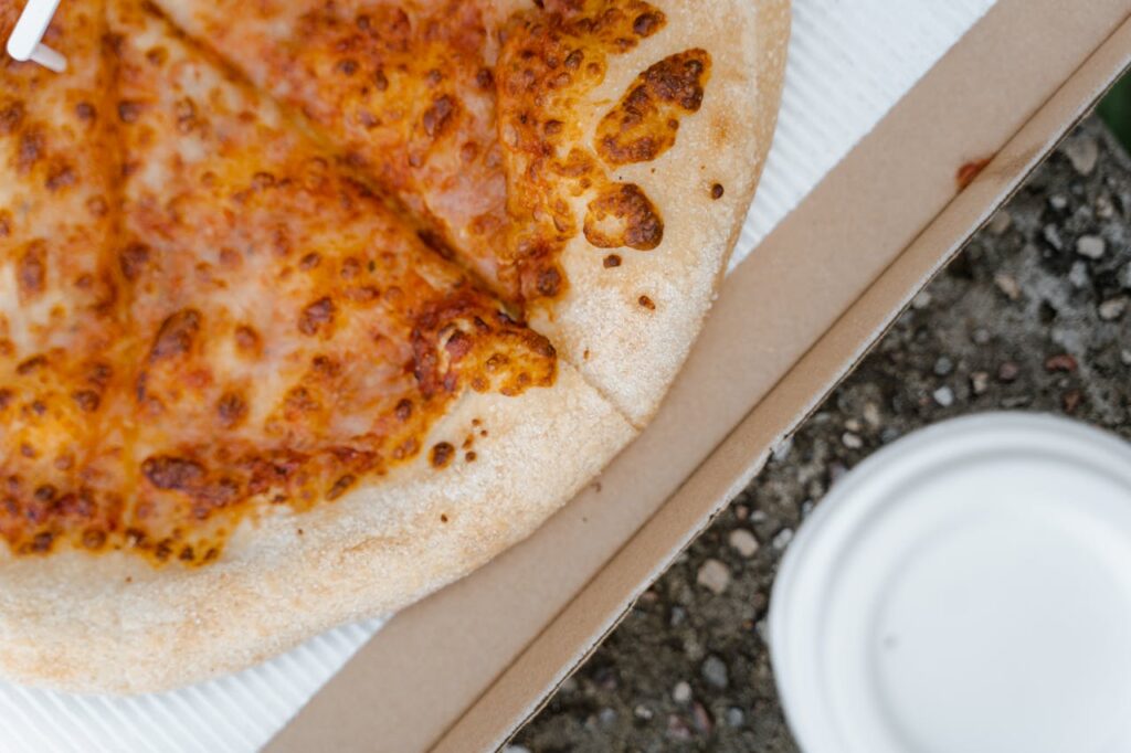 pexels-photo-8165449 A close-up shot of a cheesy pizza slice in a cardboard box, inviting and delicious.